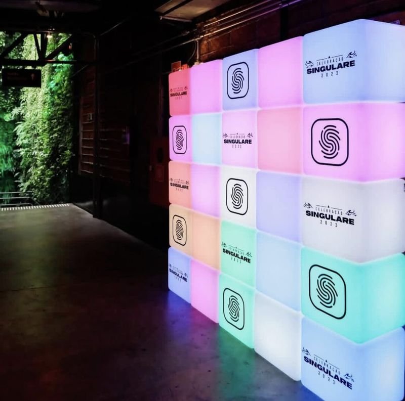 Backdrop de cubos LED em tons claros com a marca Celebração Singulare 2023 e um ícone de digital