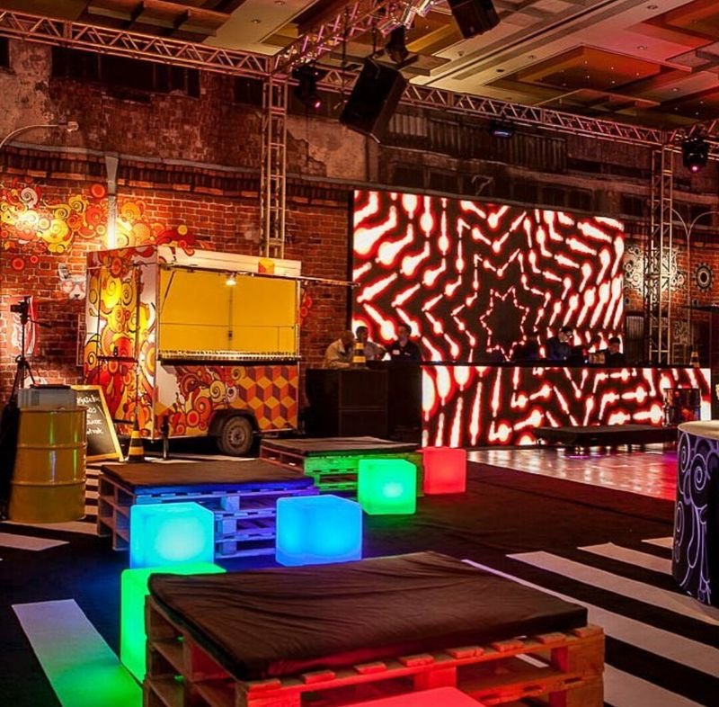 Galpão de festa com treliças, painel de LED e cubos LED verdes, azuis e vermelhos