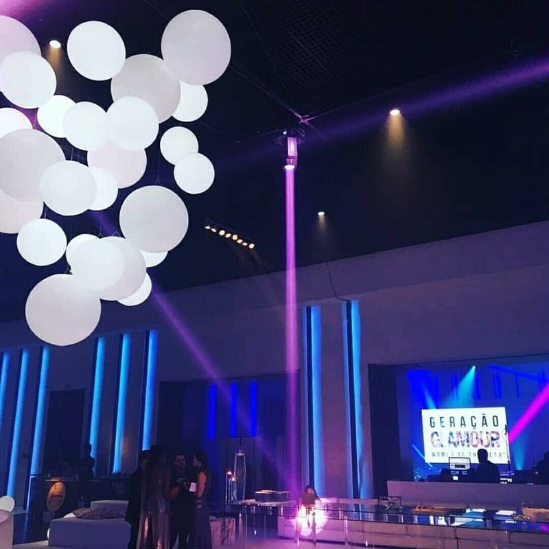 Palco de evento com esferas LED brancas suspensas e puffs iluminados na pista